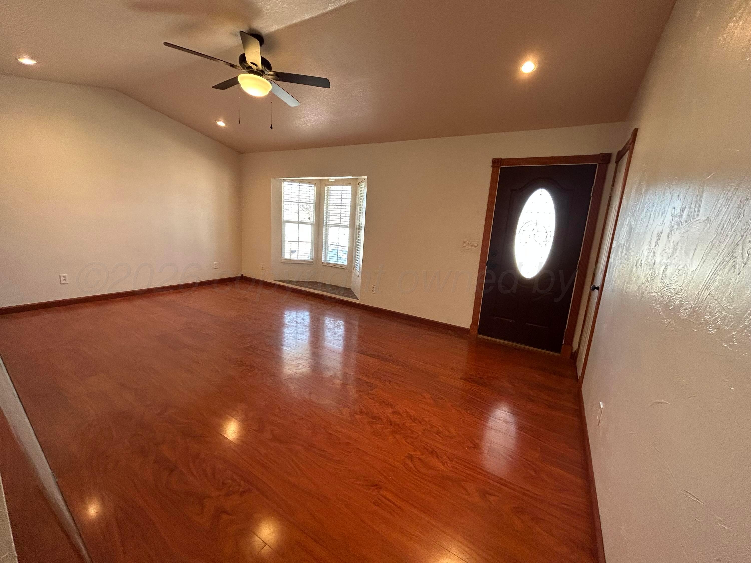 923 Elmore Street Borger, TX 79007 - Photo 2 of 18 an empty room with wooden floor and windows