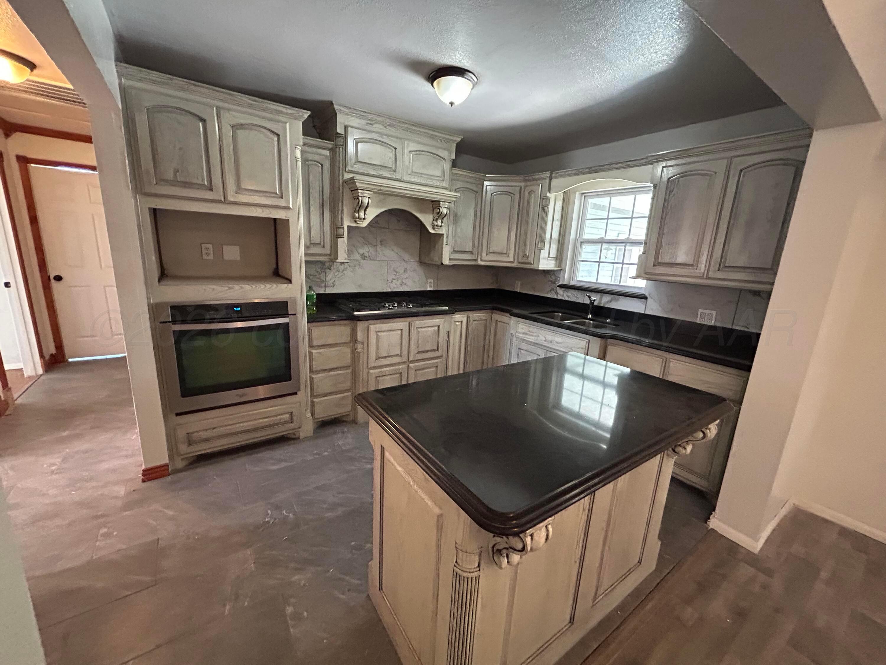 923 Elmore Street Borger, TX 79007 - Photo 6 of 18 a kitchen with granite countertop a stove sink and microwave