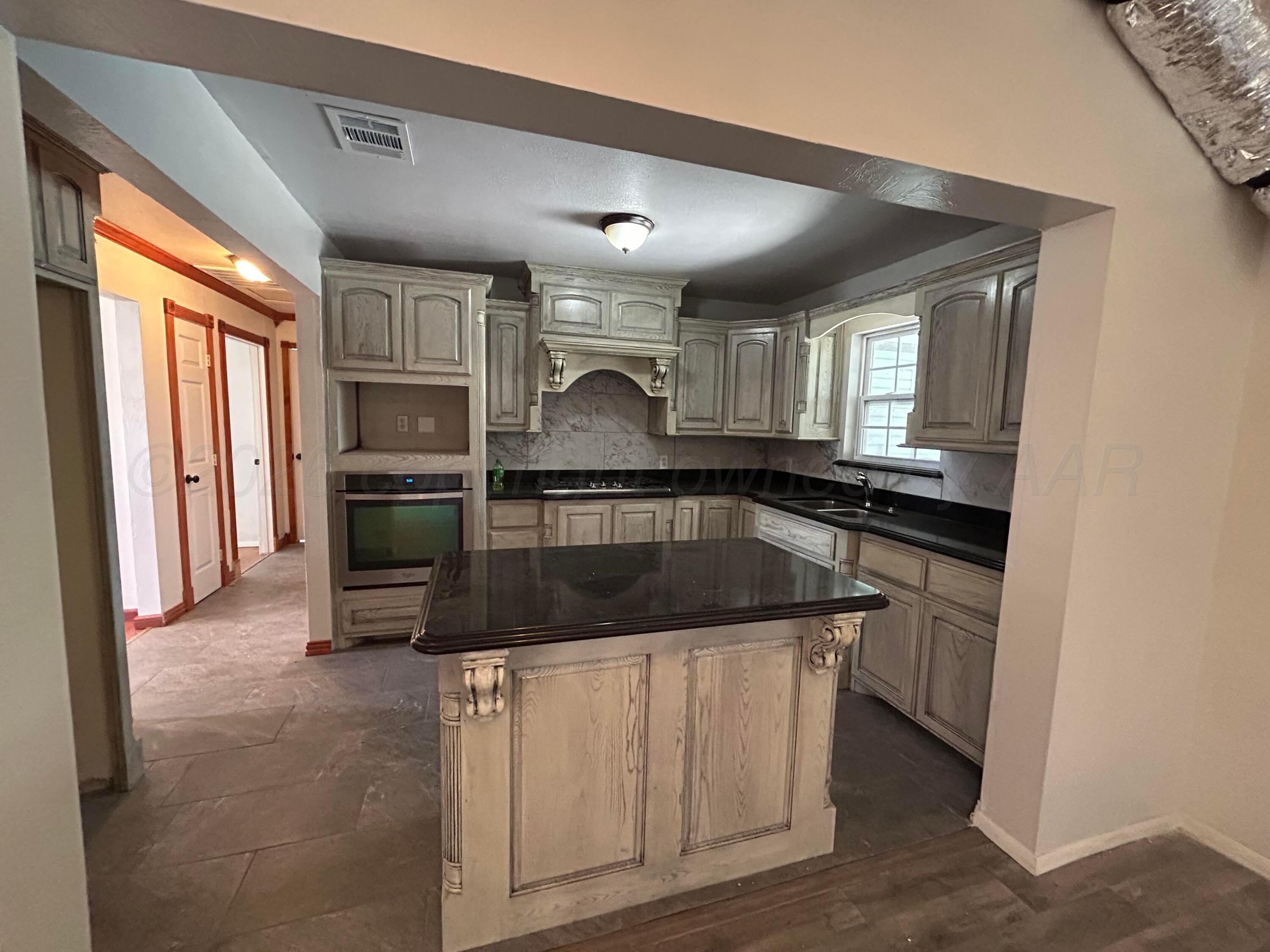 923 Elmore Street Borger, TX 79007 - Photo 7 of 18 a kitchen with kitchen island granite countertop a sink appliances and cabinets