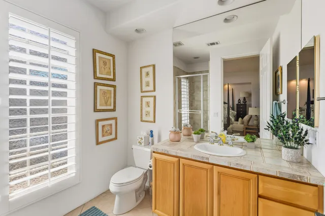 a bathroom with a granite countertop toilet sink and mirror