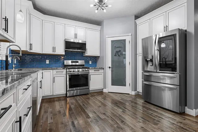 a kitchen with cabinets stainless steel appliances and wooden floor