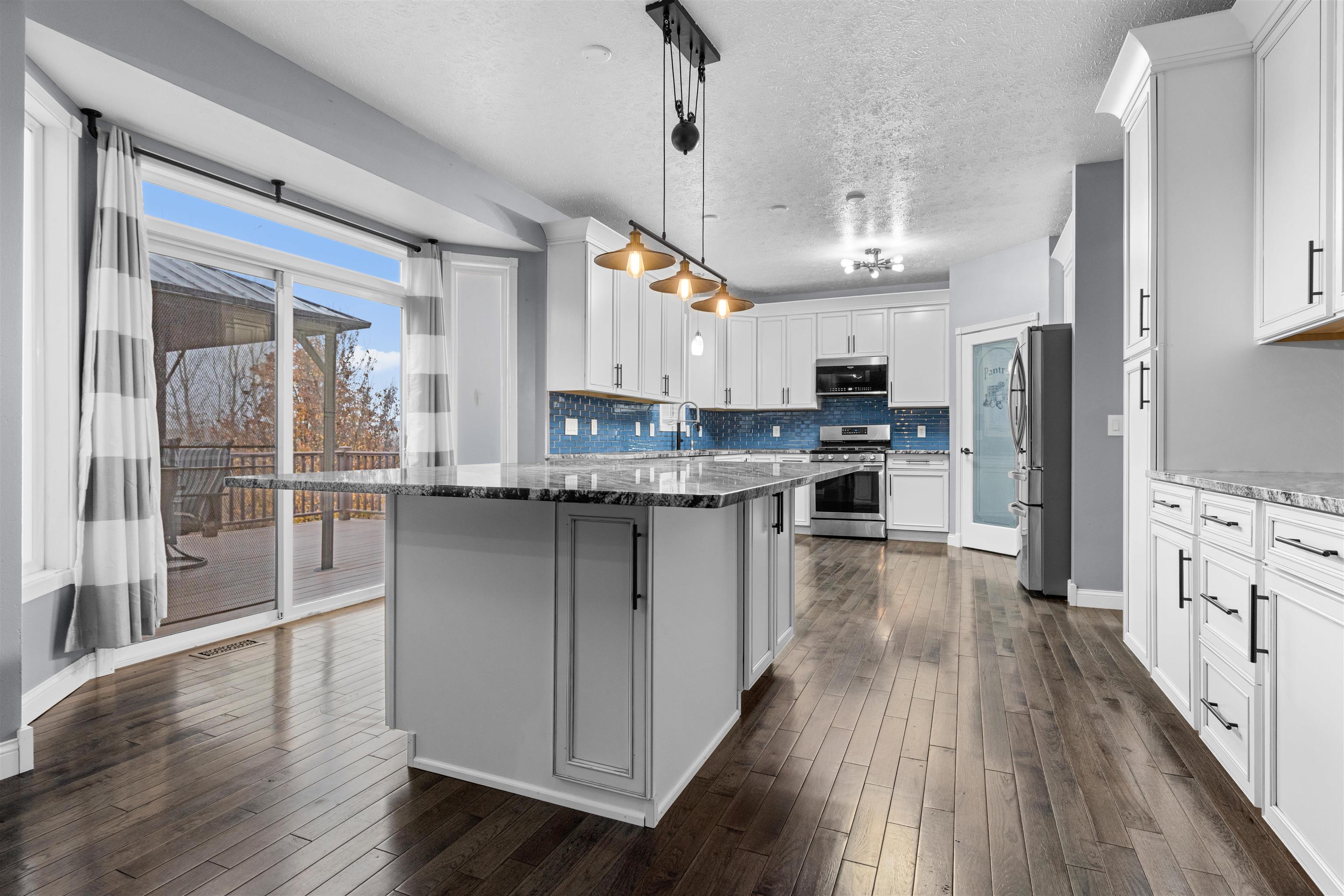 8507 Crooked Bend Road Machesney Park, IL 61115 - Photo 29 of 33 a kitchen with stainless steel appliances granite countertop a refrigerator a stove top oven a sink dishwasher and white cabinets with wooden floor