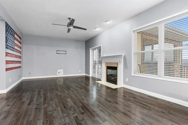 an empty room with wooden floor fireplace and windows