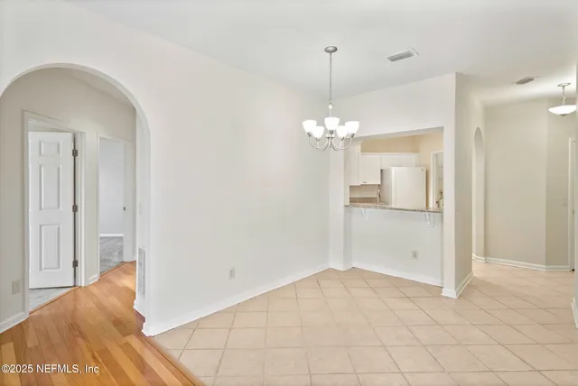 a view of a hallway with wooden floor and chandelier