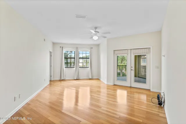 a view of an empty room with a window and wooden floor