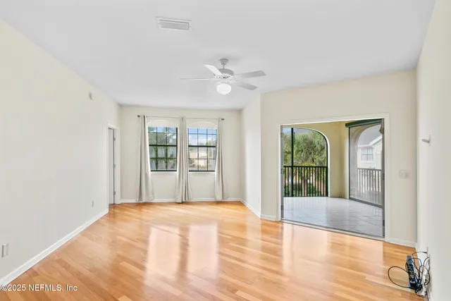 a view of empty room with wooden floor and fan