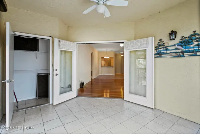 a view of an empty room with wooden floor and a ceiling fan