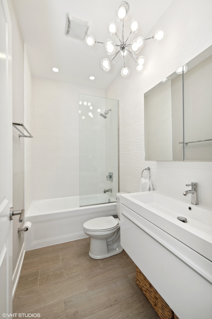 3003 North California Avenue, Unit 2N Chicago, IL 60618 - Photo 13 of 17 a bathroom with a white tub shower and toilet