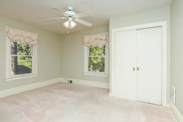 an empty room with a ceiling fan and a window