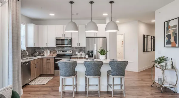 a kitchen with stainless steel appliances granite countertop a stove top oven a refrigerator a sink and a dining table with wooden floor