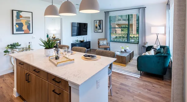 a view of kitchen island with stainless steel appliances kitchen island granite countertop a table chairs in it and a flat screen tv