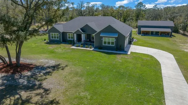 an aerial view of residential house with outdoor space and trees all around
