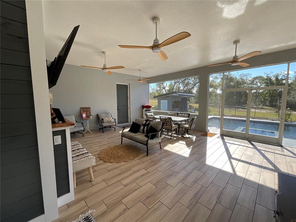 11707 Southeast 101st Court Road Belleview, FL 34420 - Photo 56 of 84 a living room with furniture a flat screen tv and a floor to ceiling window