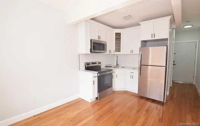 a kitchen with a refrigerator stove and white cabinets