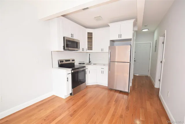a kitchen with a refrigerator a stove top oven and wooden floor