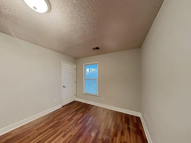 a view of an empty room with wooden floor and windows
