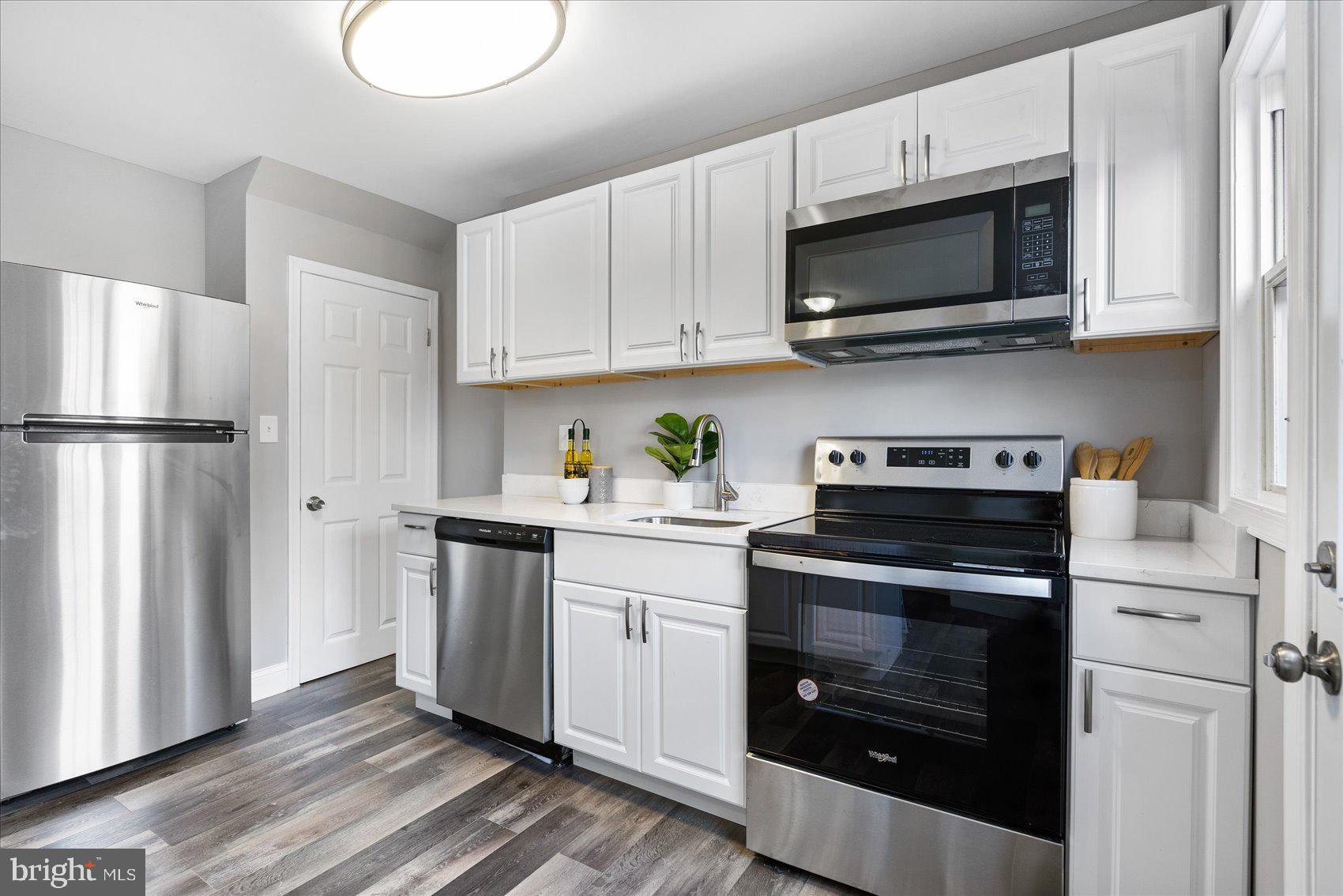 1932 Haselmere Road Dundalk, MD 21222 - Photo 14 of 40 a kitchen with stainless steel appliances white cabinets and a stove a refrigerator with wooden floor