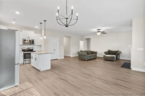 a living room with furniture kitchen view and a wooden floor