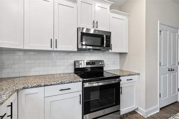 a kitchen with stainless steel appliances granite countertop white cabinets granite counter tops and a hard wood floors