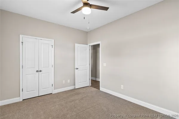 a view of an empty room and chandelier fan