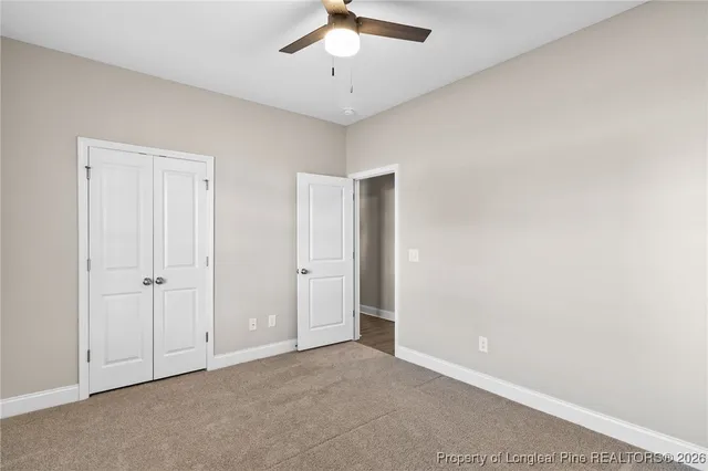 a view of an empty room and chandelier fan