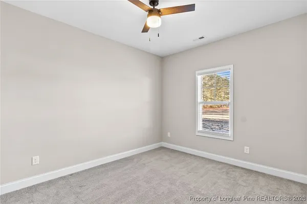an empty room with windows and ceiling fan