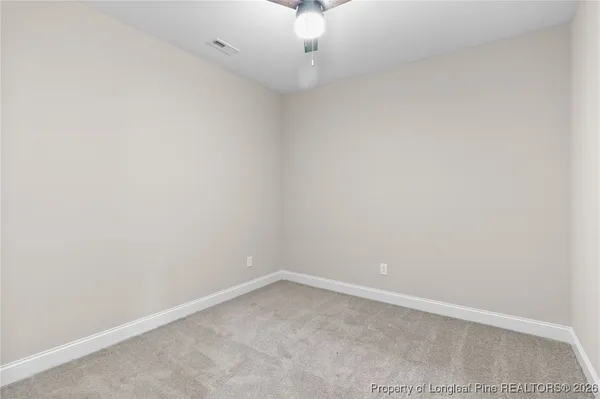 an empty room with a ceiling fan and carpet