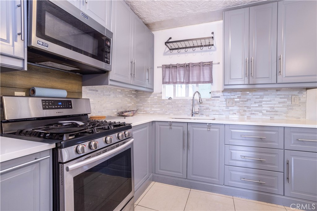 13655 Chase Street Arleta, CA 91331 - Photo 8 of 34 a kitchen with stainless steel appliances granite countertop a stove a sink and a microwave