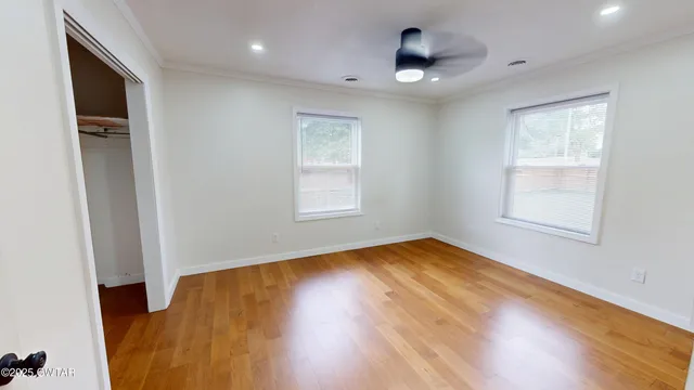 a view of an empty room with wooden floor and a window
