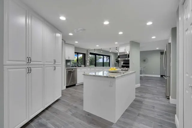 a large kitchen with stainless steel appliances a large counter top and wooden floors