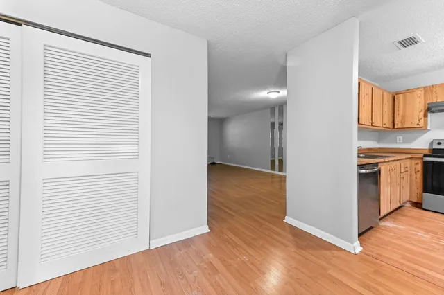 a view of a kitchen with a fridge and wooden floor