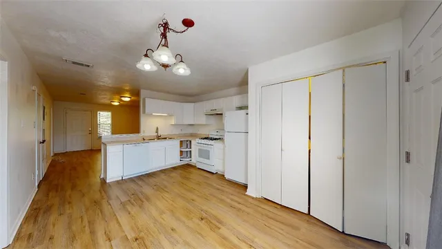 a kitchen with stainless steel appliances white cabinets and wooden floor