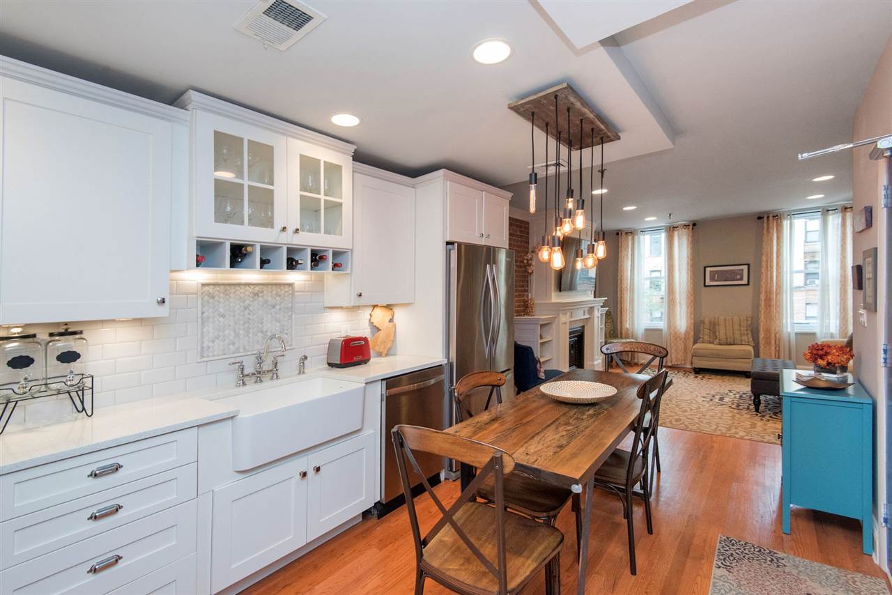 a kitchen with a dining table chairs sink and white cabinets