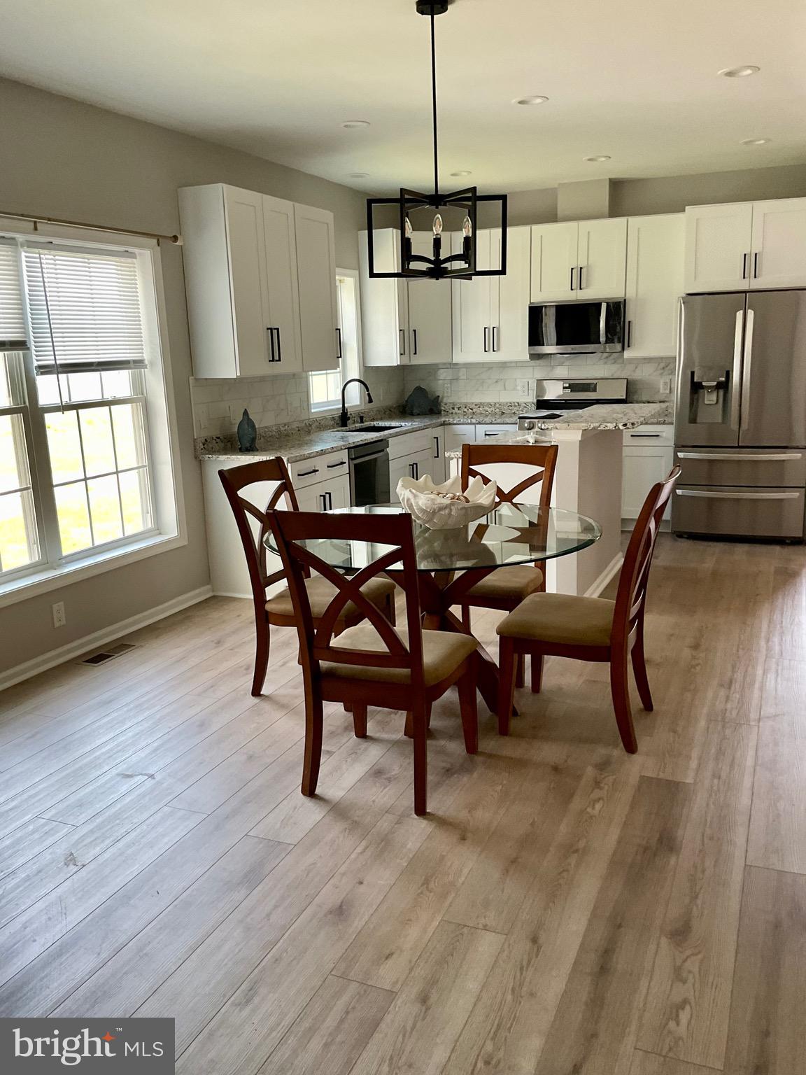 10342 Friendship Road Berlin, MD 21811 - Photo 34 of 35 a kitchen with stainless steel appliances kitchen island granite countertop a stove a refrigerator a sink a dining table and chairs with wooden floor