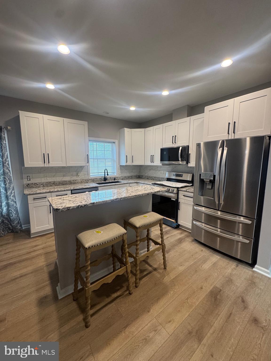 10342 Friendship Road Berlin, MD 21811 - Photo 9 of 28 a kitchen with stainless steel appliances a refrigerator a stove a sink dishwasher and a dining table with wooden floor