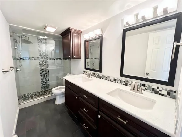 a bathroom with a double vanity sink toilet mirror and shower