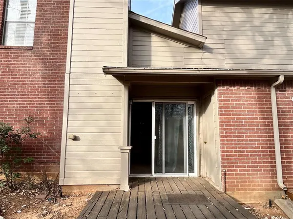 a backyard of a house with large trees and a wooden fence