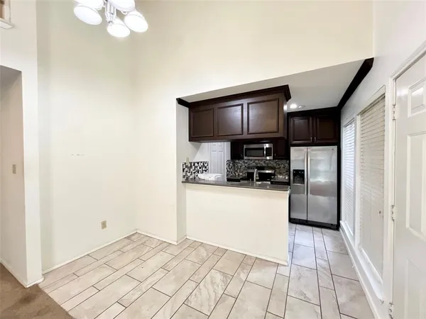 a kitchen with granite countertop a refrigerator a stove top oven a sink and dishwasher