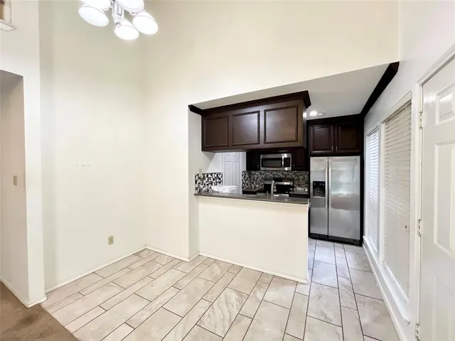 a kitchen with granite countertop a refrigerator a stove top oven a sink and dishwasher