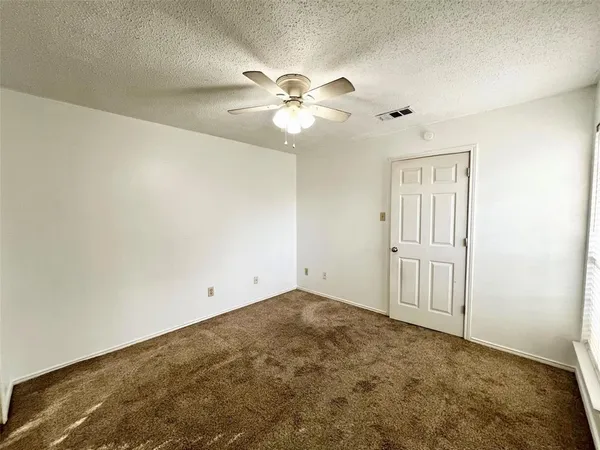 an empty room with windows and fan