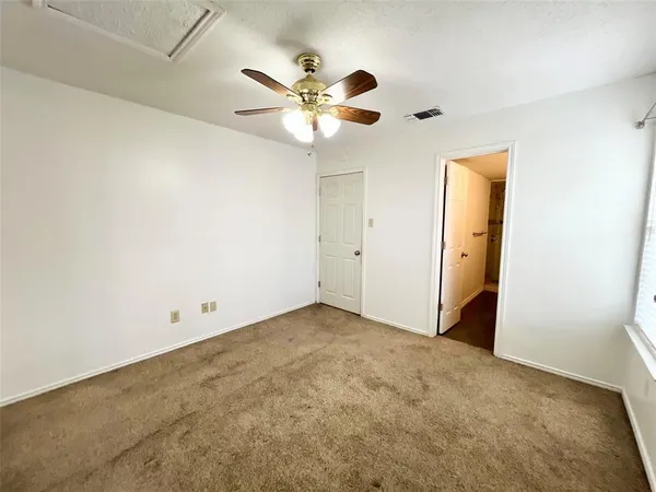 an empty room with a ceiling fan and a window