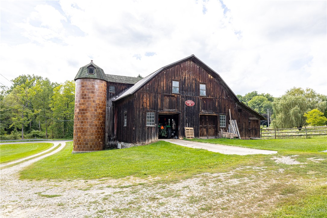 7780 Cold Springs Road Bath, NY 14810 - Photo 25 of 50 A historic wooden barn with an integrated silo stands on a gentle grassy slope.