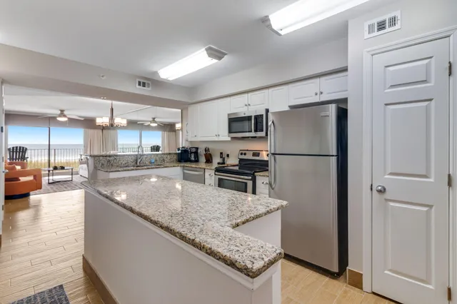 a kitchen with stainless steel appliances granite countertop a refrigerator a stove and a sink