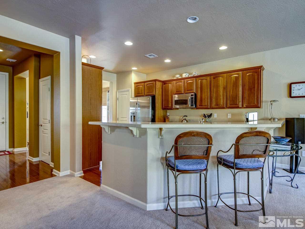 1100 Meridian Ranch Drive Reno, NV 89523 - Photo 10 of 25 a kitchen with kitchen island granite countertop wooden cabinets and a refrigerator