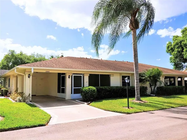 a view of a house with a yard and palm trees