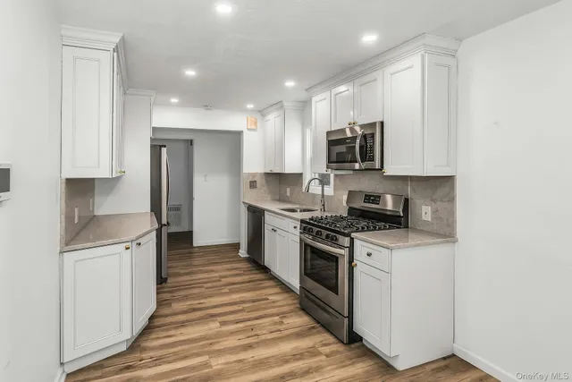 a kitchen with stainless steel appliances granite countertop a stove top oven a sink and a refrigerator