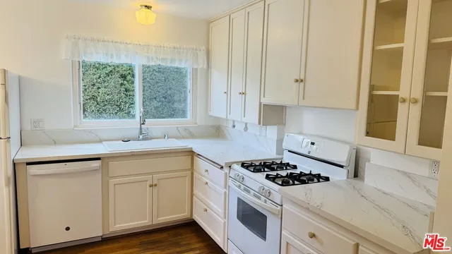 a kitchen with white cabinets and appliances