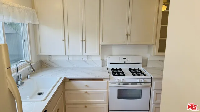 a kitchen with granite countertop white cabinets and white stove