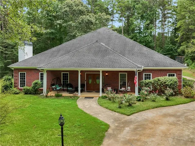 a front view of a house with garden and trees
