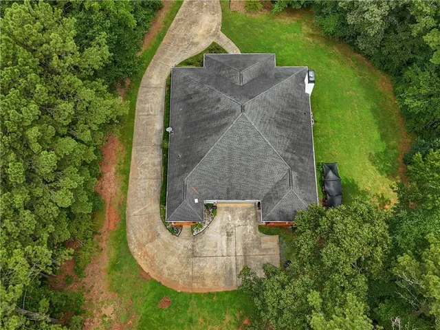 an aerial view of a house with outdoor space and trees all around